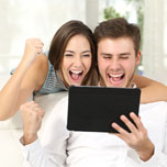 excited couple on tablet
